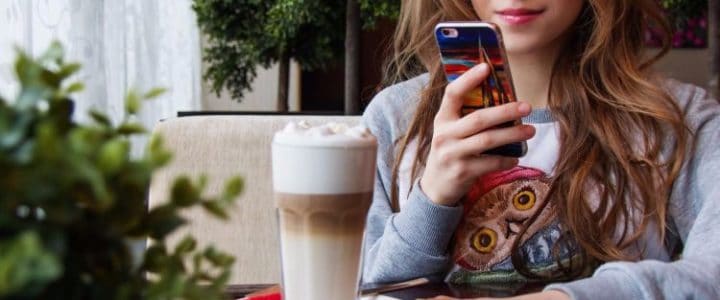 Girl making Mobile Payment whilst drinking Coffee