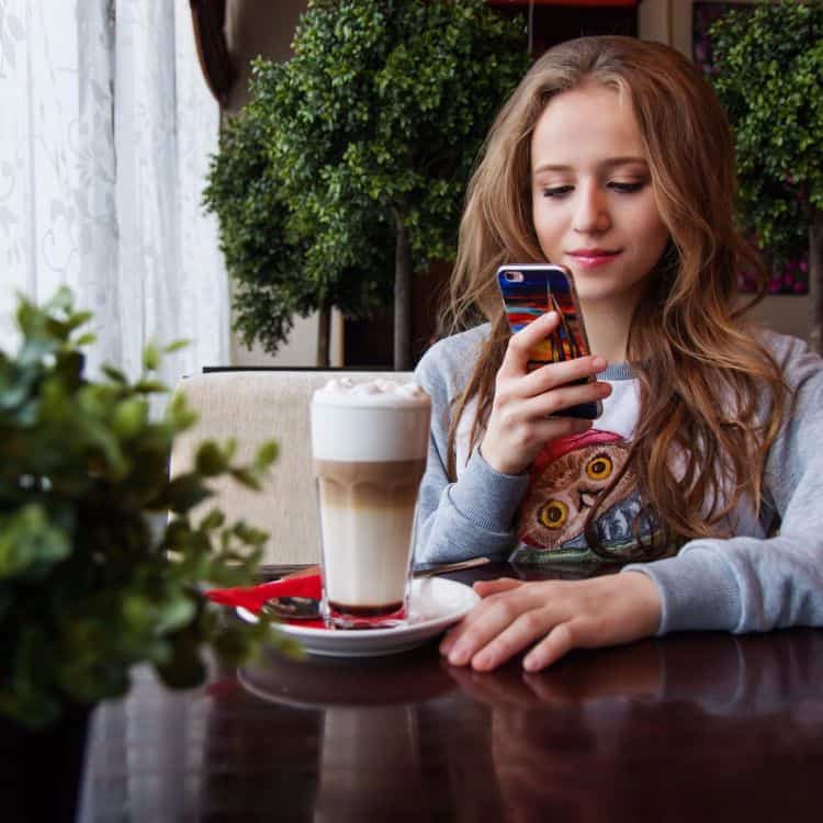 Girl making Mobile Payment whilst drinking Coffee